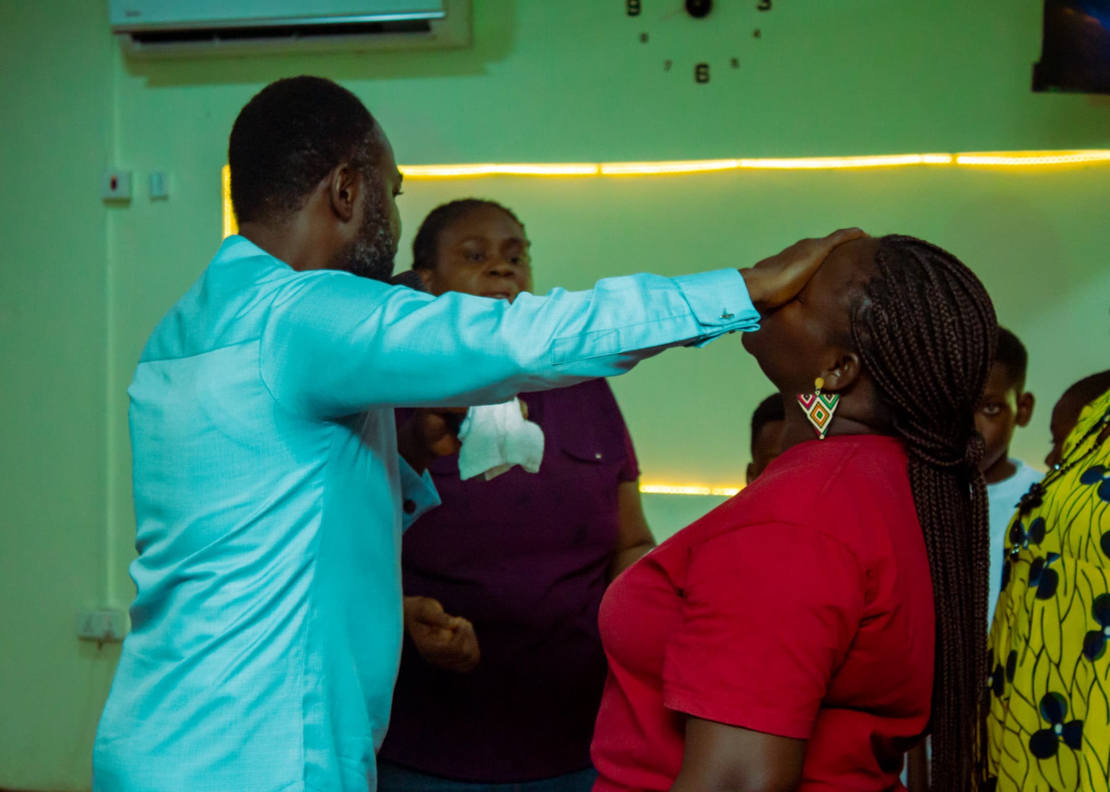Apostle Benjamin Asamoah praying for a woman in red