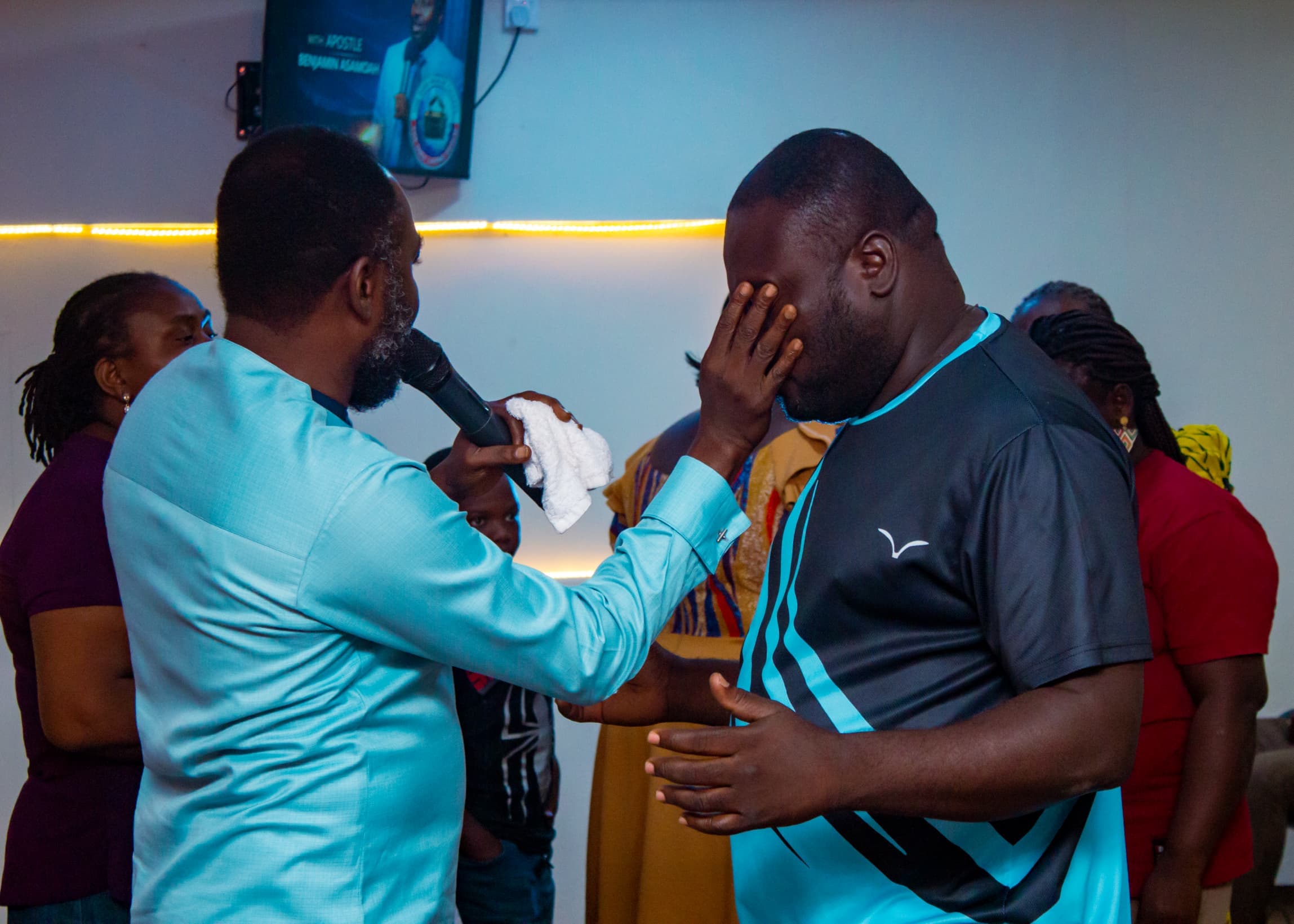 Apostle Benjamin Asamoah praying for a man during a service