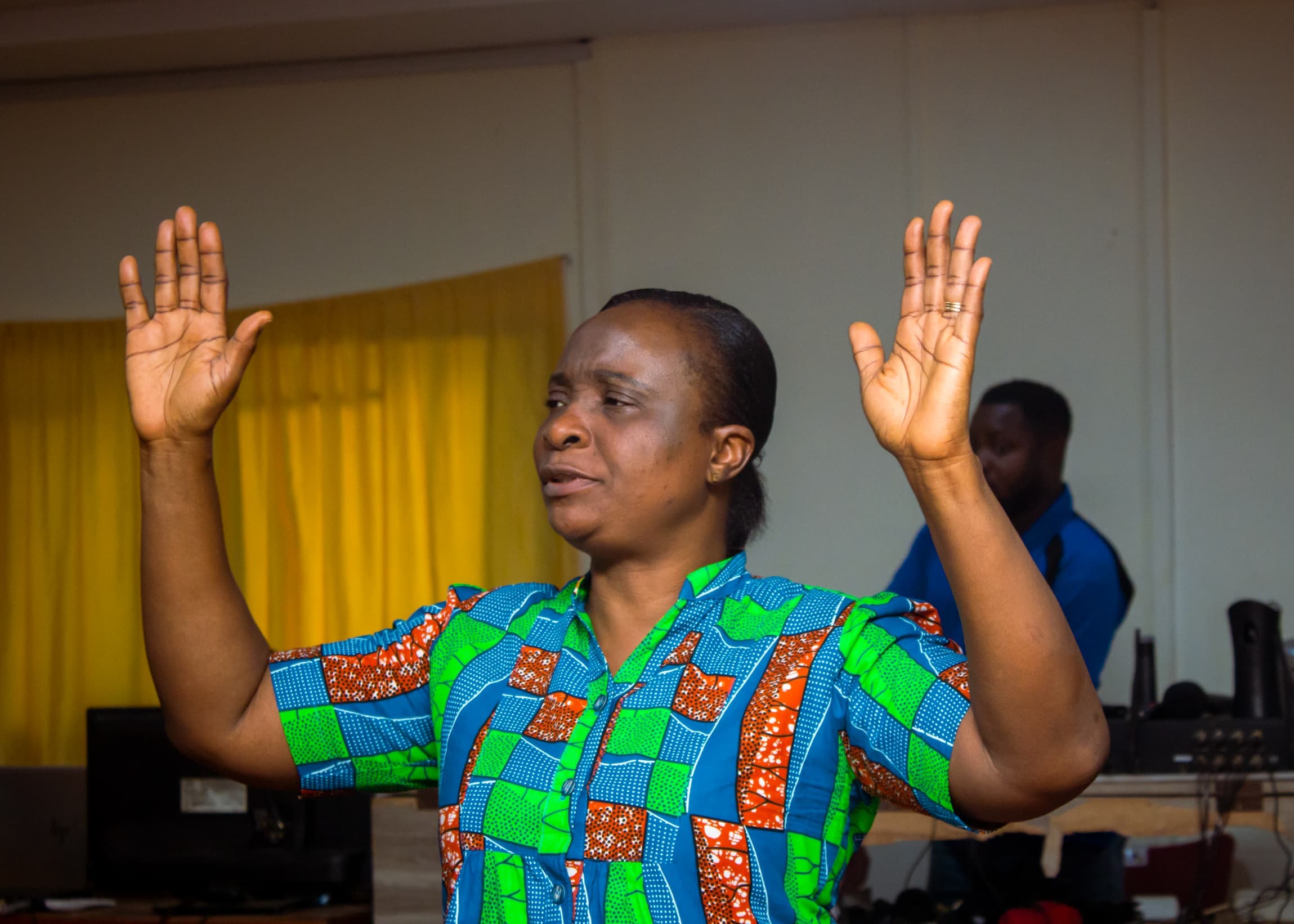 Woman in Ankara print worshipping with raised hands