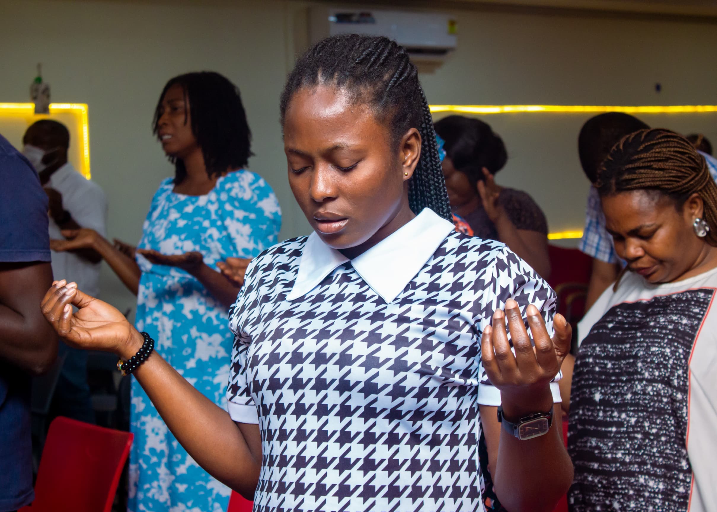 Young woman praying with raised hands in the congregation