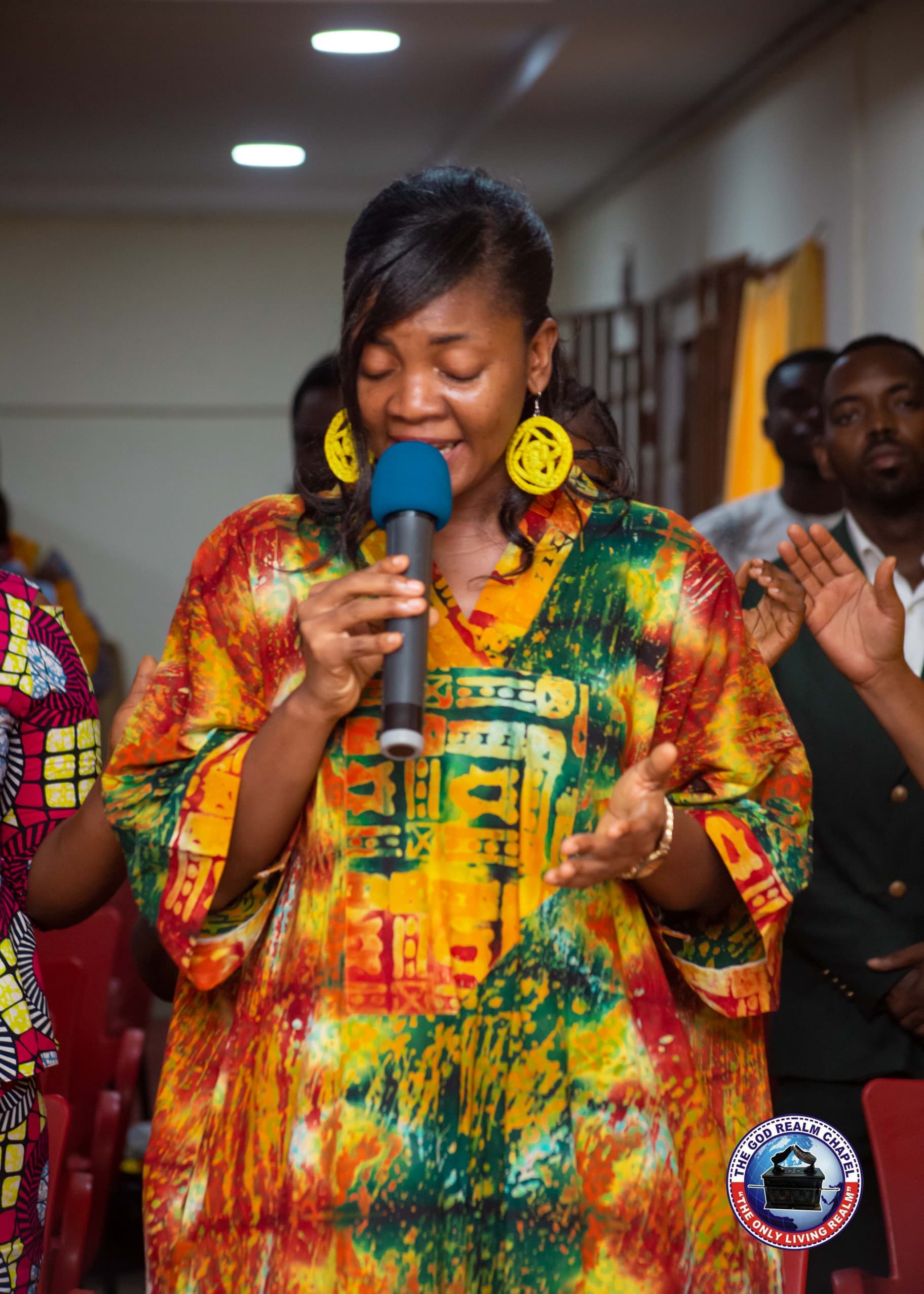 Woman leading worship with a microphone at The God Realm Chapel