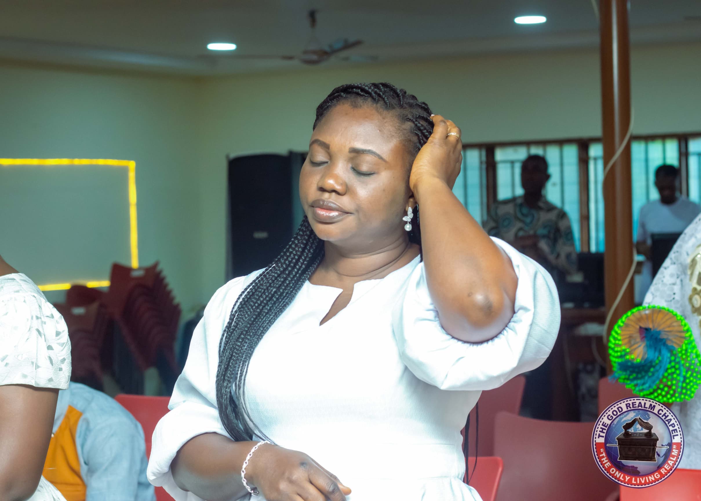 Woman in white worshipping with eyes closed at The God Realm Chapel
