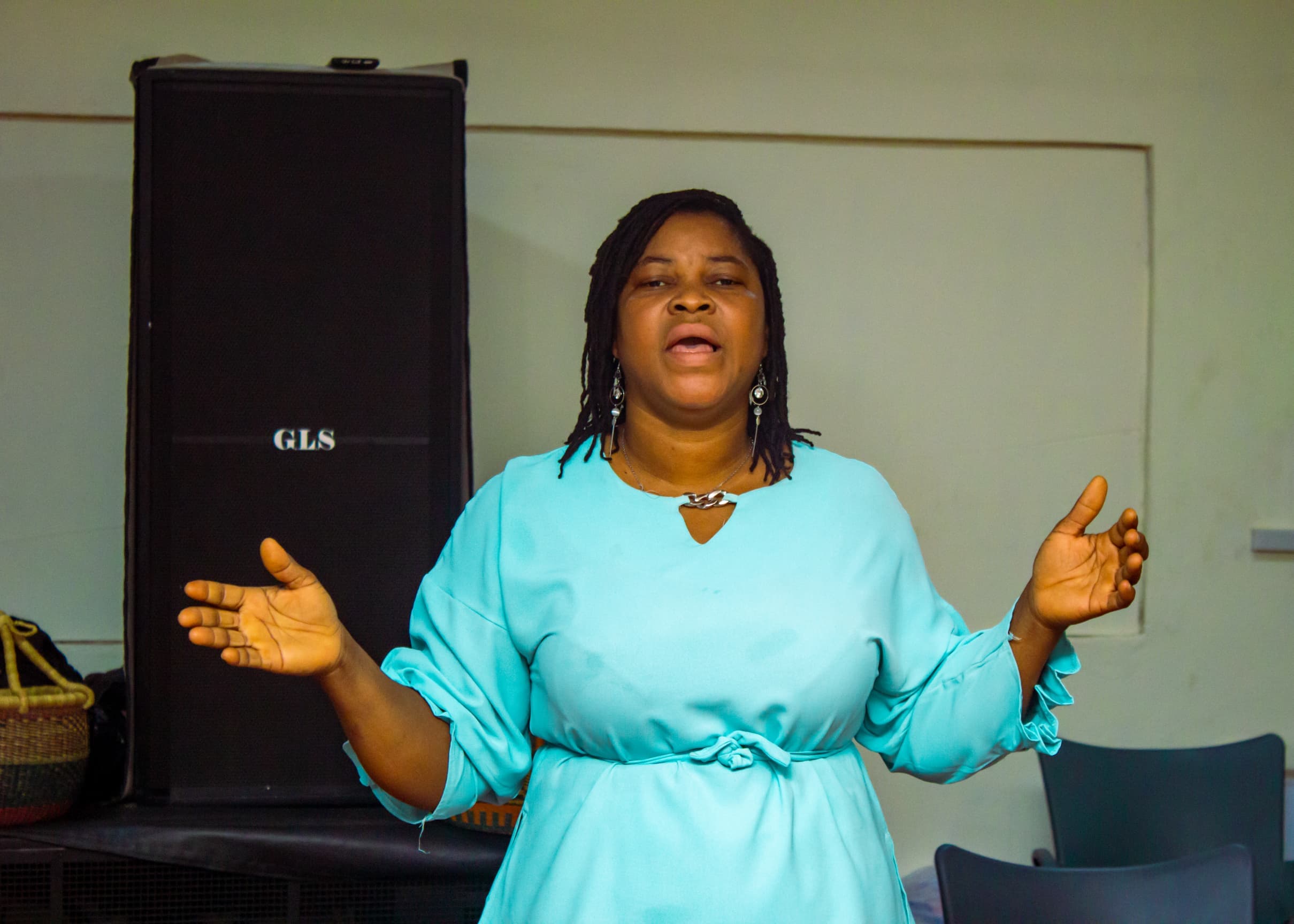 Woman in turquoise leading worship with outstretched arms