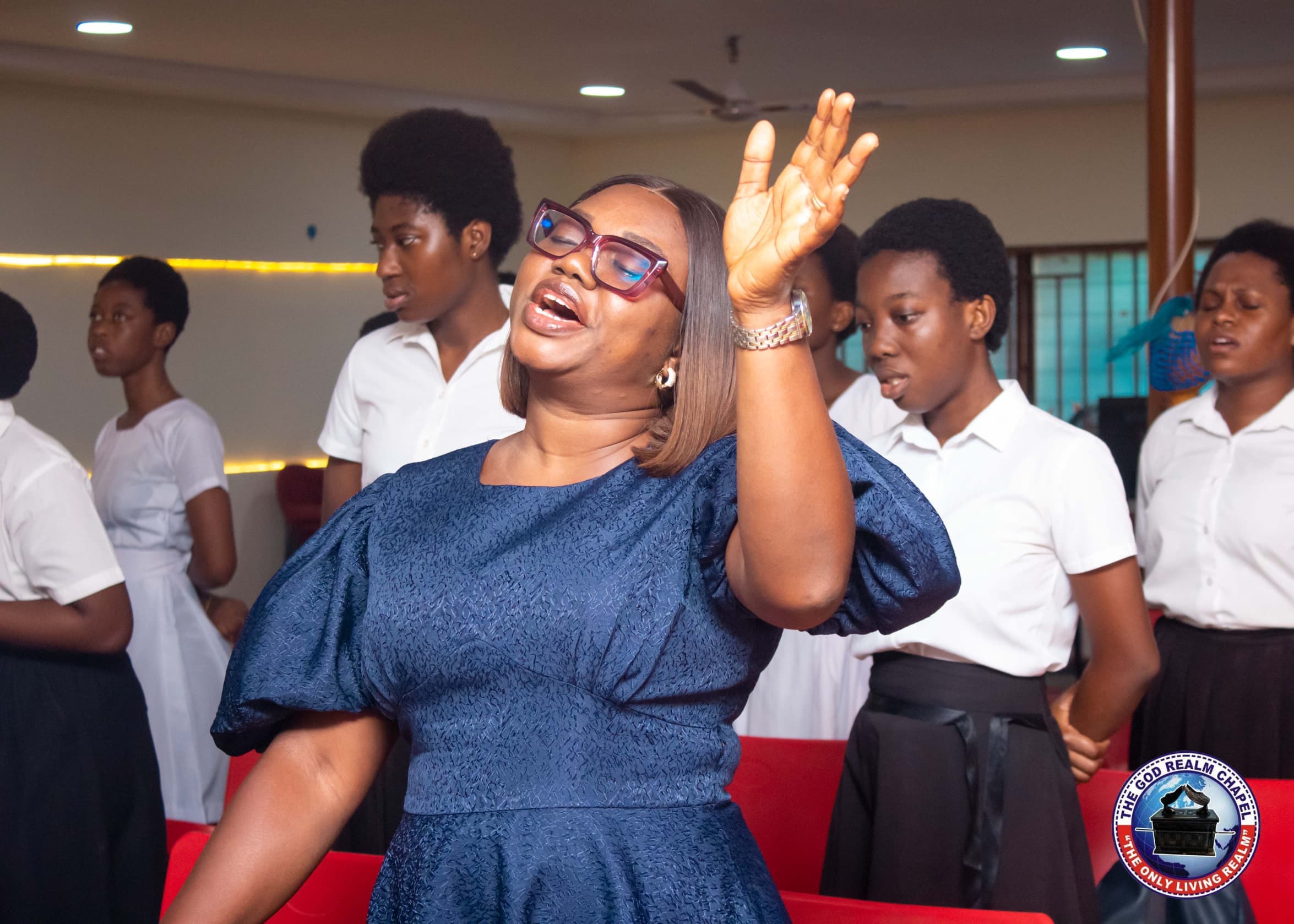 Worship leader praying with the choir at The God Realm Chapel